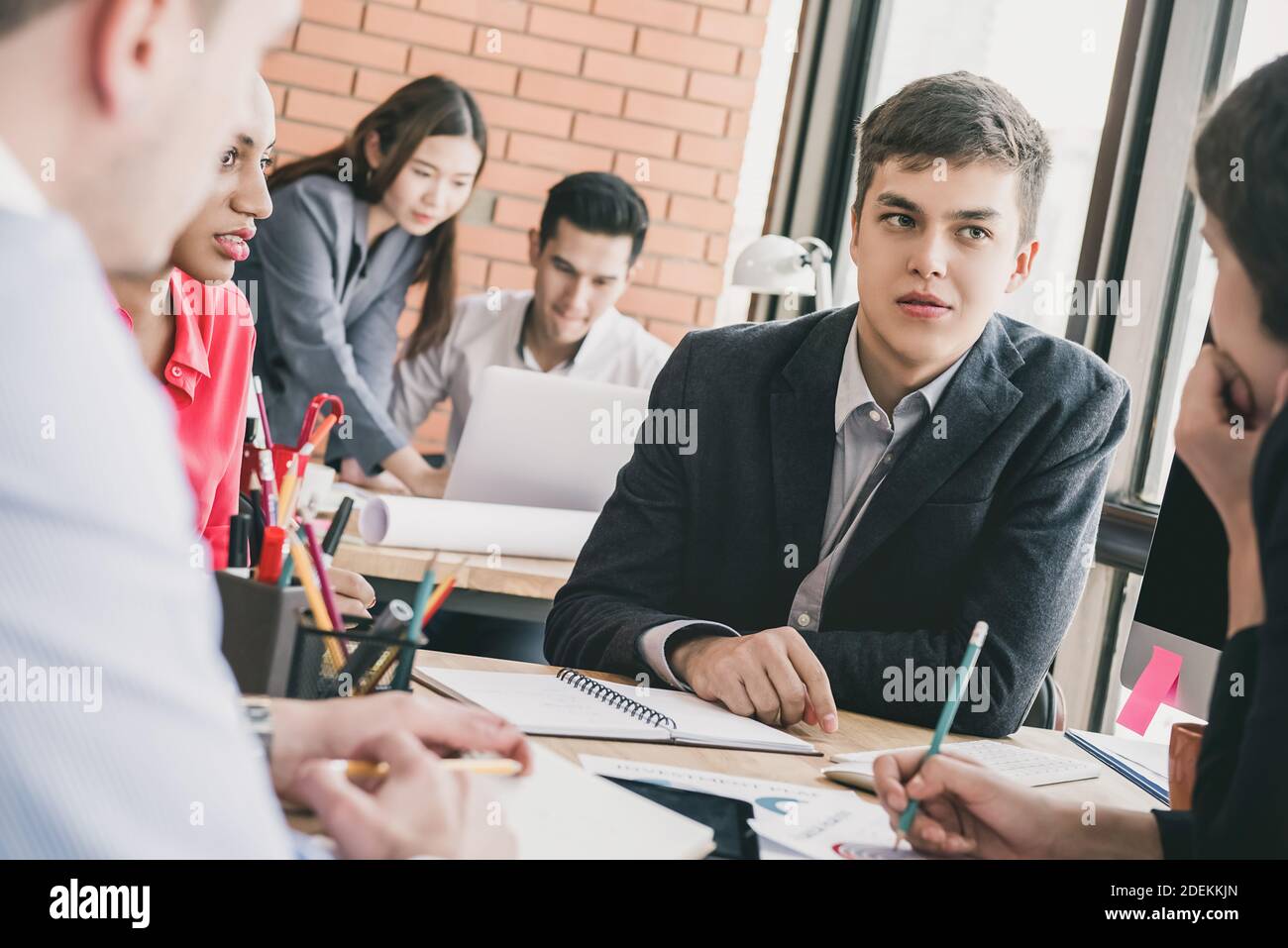 Young multiethnic business team meeting at the office desk seriously discussing project Stock Photo