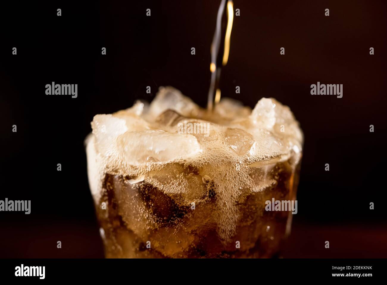 Close up of sparkling carbonated cold fresh cola drink being poured into the glass with overflowed frothy bubble on top Stock Photo