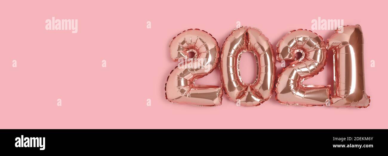 Banner with 2021 made from rose gold color balloons on a pink background with place for text. Stock Photo