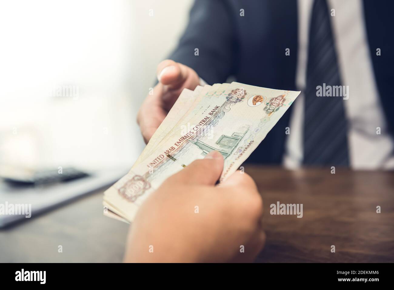 Rich businessman giving United Arab Emirates dirham money banknotes to his partner for business deal Stock Photo