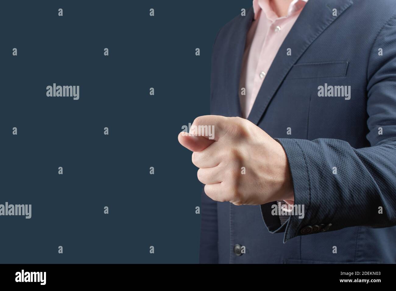 businessman shows fig gesture. Businessman in a blue suit shows a fig sign on blue background. gesture of contempt or rejection of unacceptable condit Stock Photo
