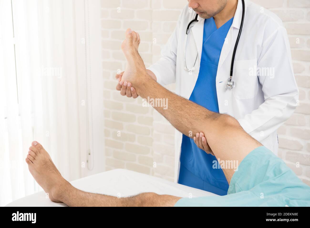 Doctor or physiotherapist giving the expert treatment to the broken leg patient on the bed for a good recovery Stock Photo