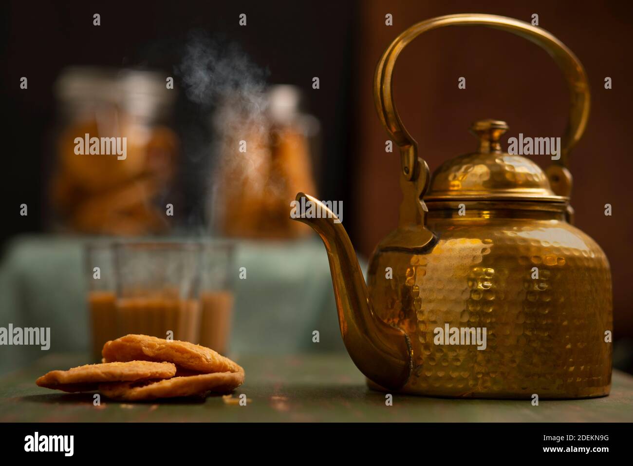 Brass kettle kept next to matthis with tea glasses and snacks kept in the  background at a tea stall Stock Photo - Alamy