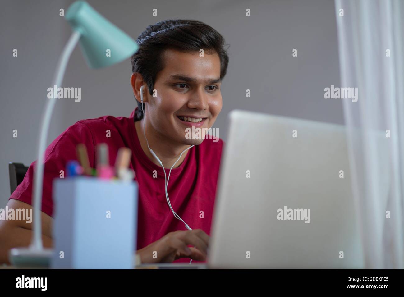 COLLEGE STUDENT WATCHING A MOVIE ON HIS LAPTOP IN EXCITEMENT Stock Photo
