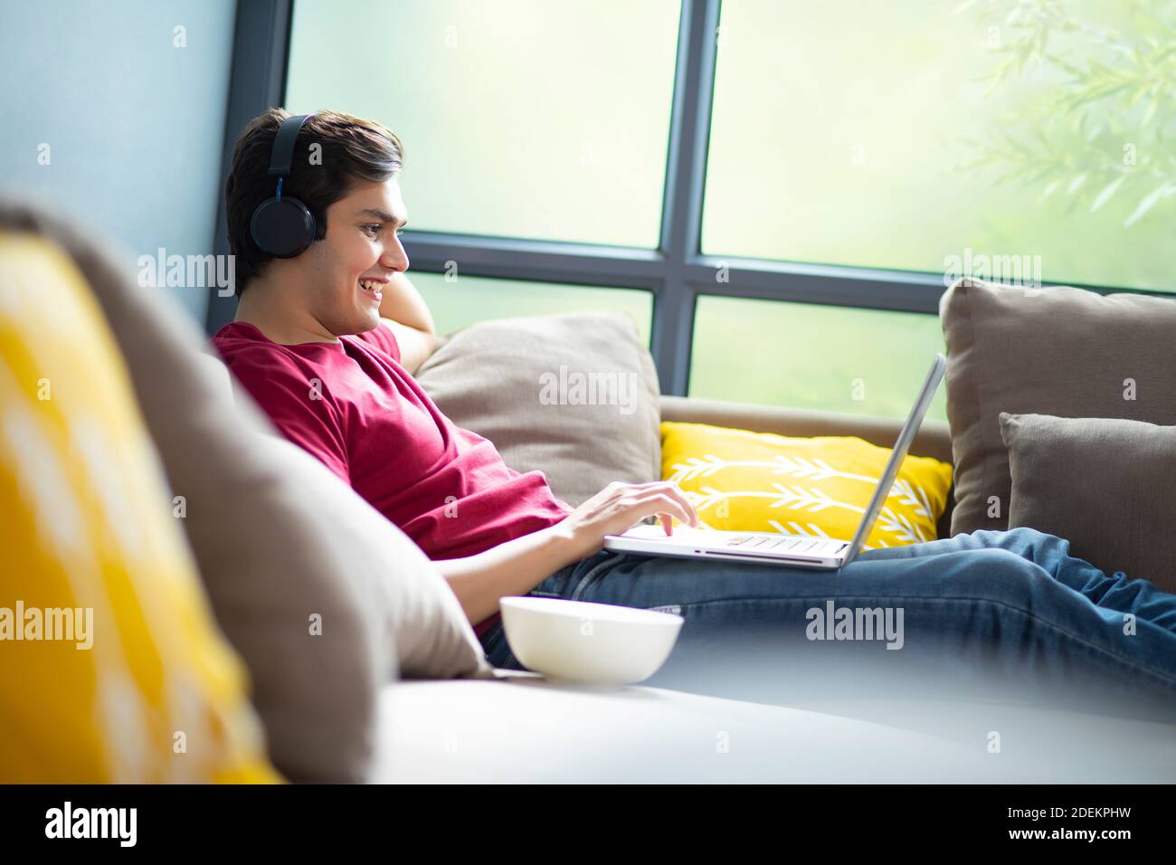 A YOUNG COLLEGE STUDENT ATTENDING ONLINE CLASS WHILE RESTING ON SOFA