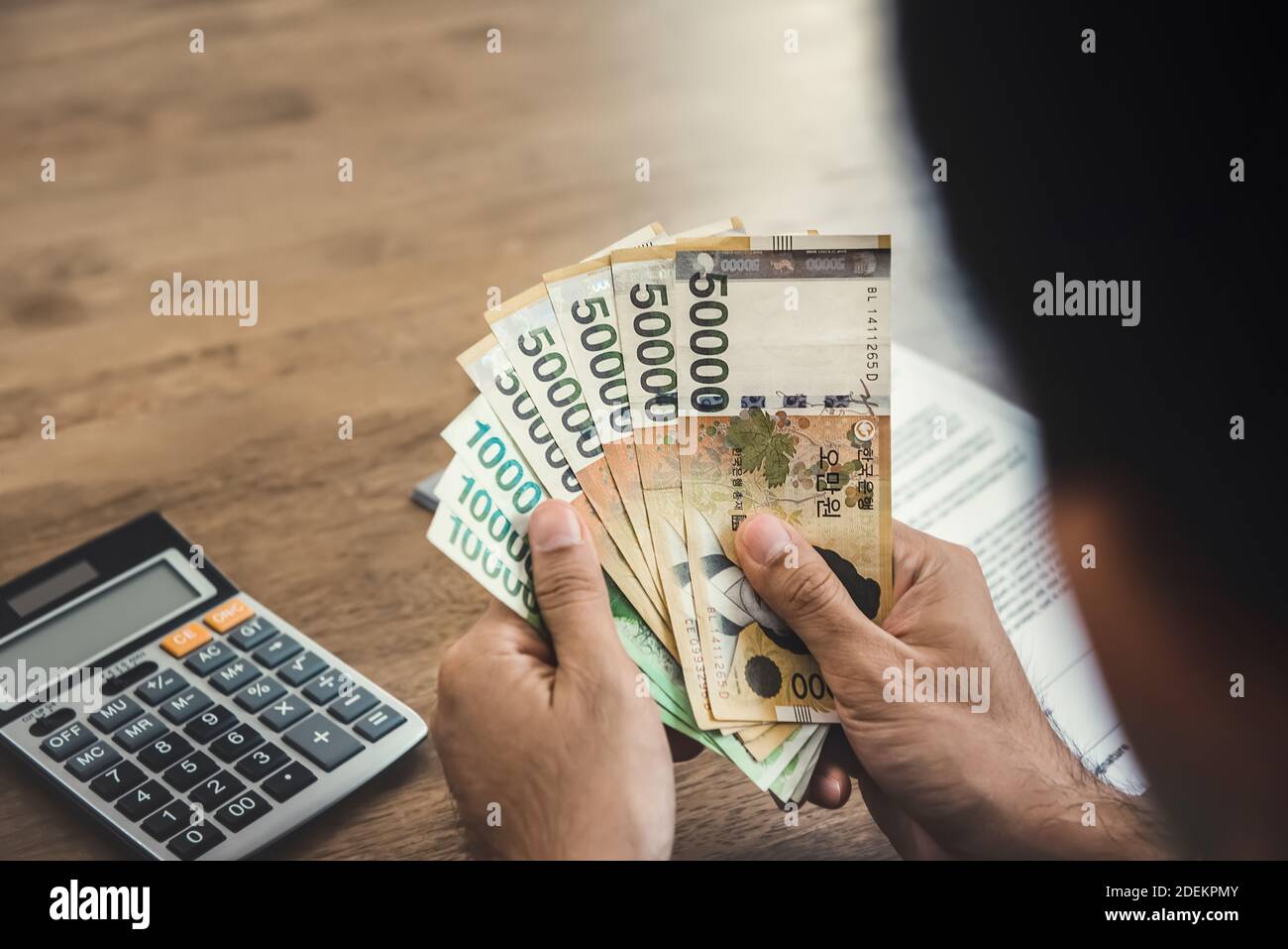 Hands of businessman holding money, South Koren won banknotes, at working desk Stock Photo