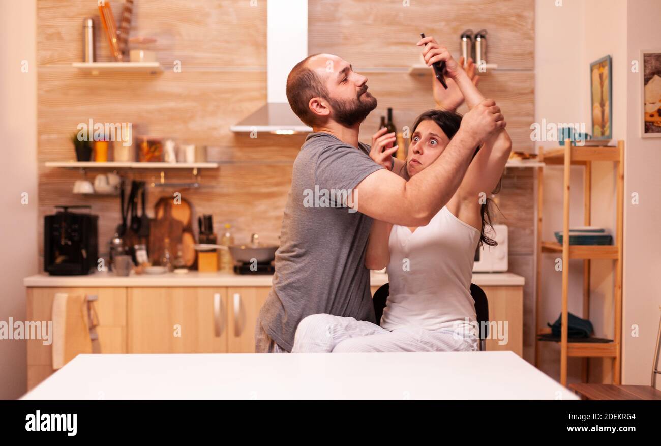Jelous husband trying to take wife phone suspecting her of cheating with another man. Frustrated offended irritated accusing woman of infidelity arguing her. Stock Photo
