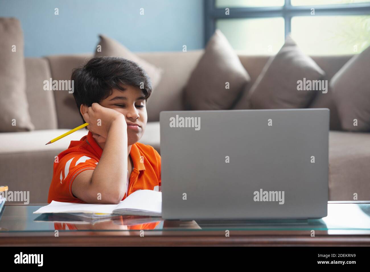 A YOUNG SCHOOL KID FEELING SLEEPY DURING ONLINE CLASS Stock Photo