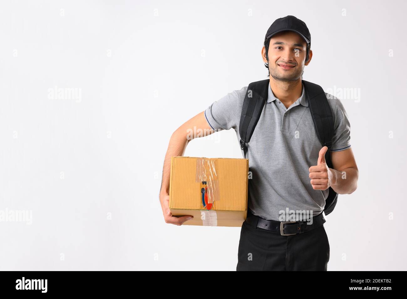 Delivery boy giving thumbs up with a box in one hand Stock Photo