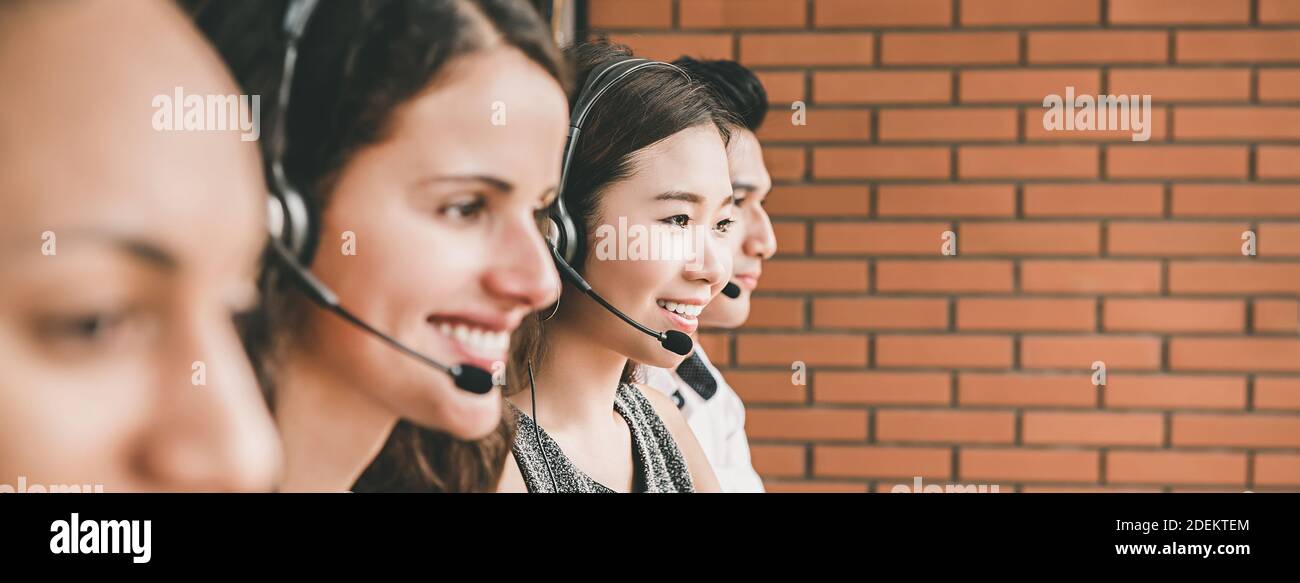 Smiling multiethic telemarketing customer service agent team working in call center - panoramic web banner Stock Photo
