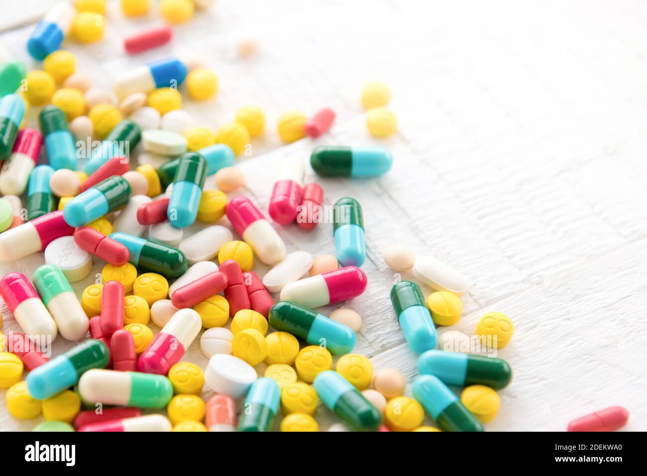 Mixed colorful pharmaceutical drugs and medicine in pill and capsule form on white table Stock Photo