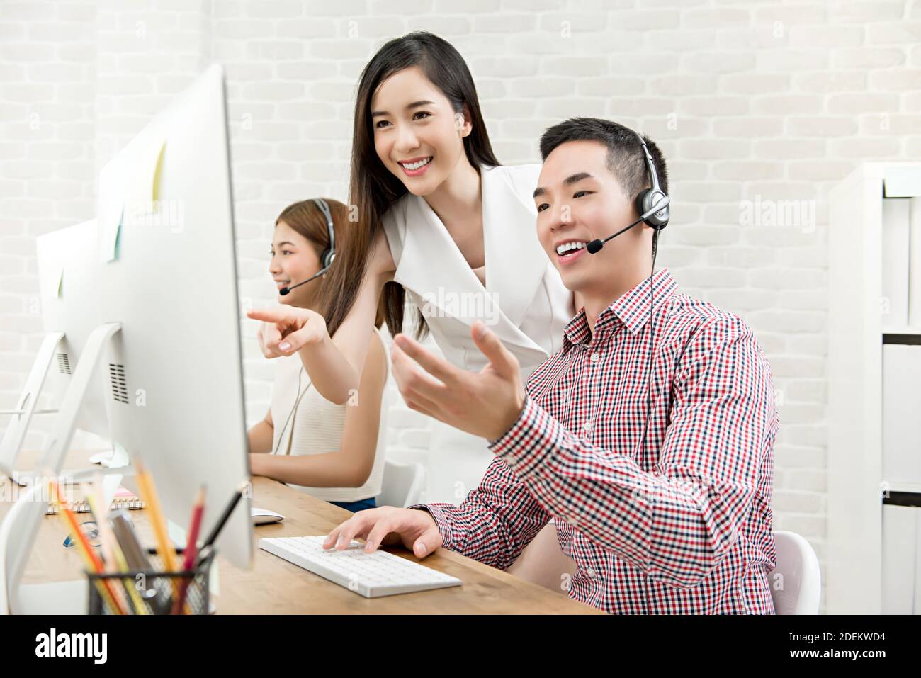 Female Asian supervisor discussing work with telemarketing customer