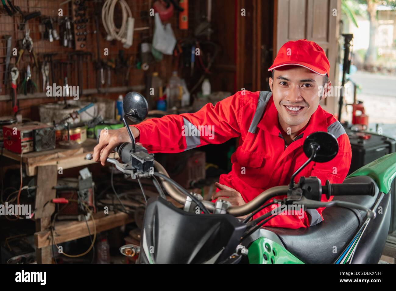 smiling mechanic in wearpack uniform checking dirt bike engines