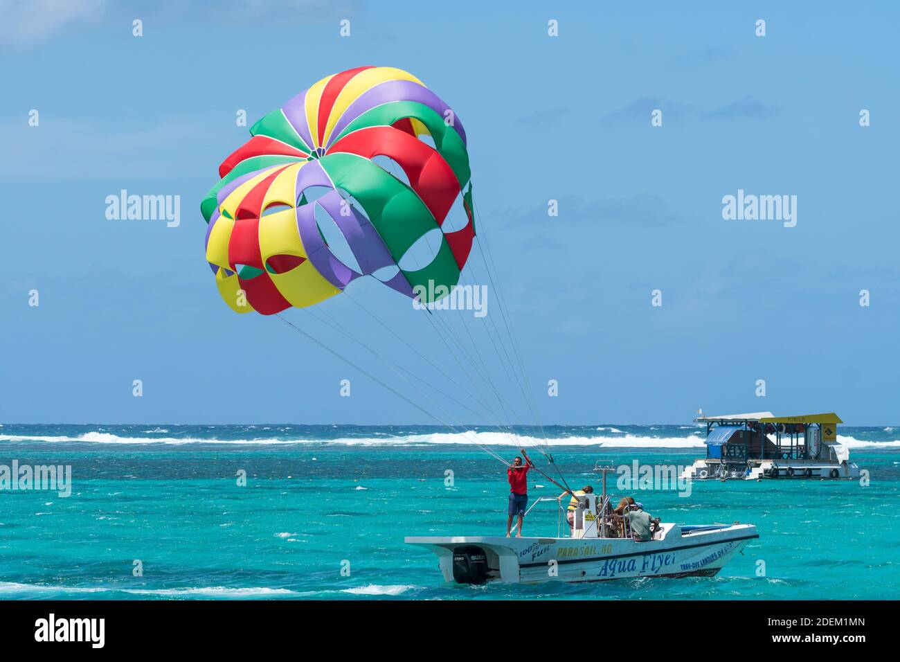 parasailing boat and parachute with people on the turquoise blue coral reef in Mauritius concept water sport activity and lifestyle Stock Photo