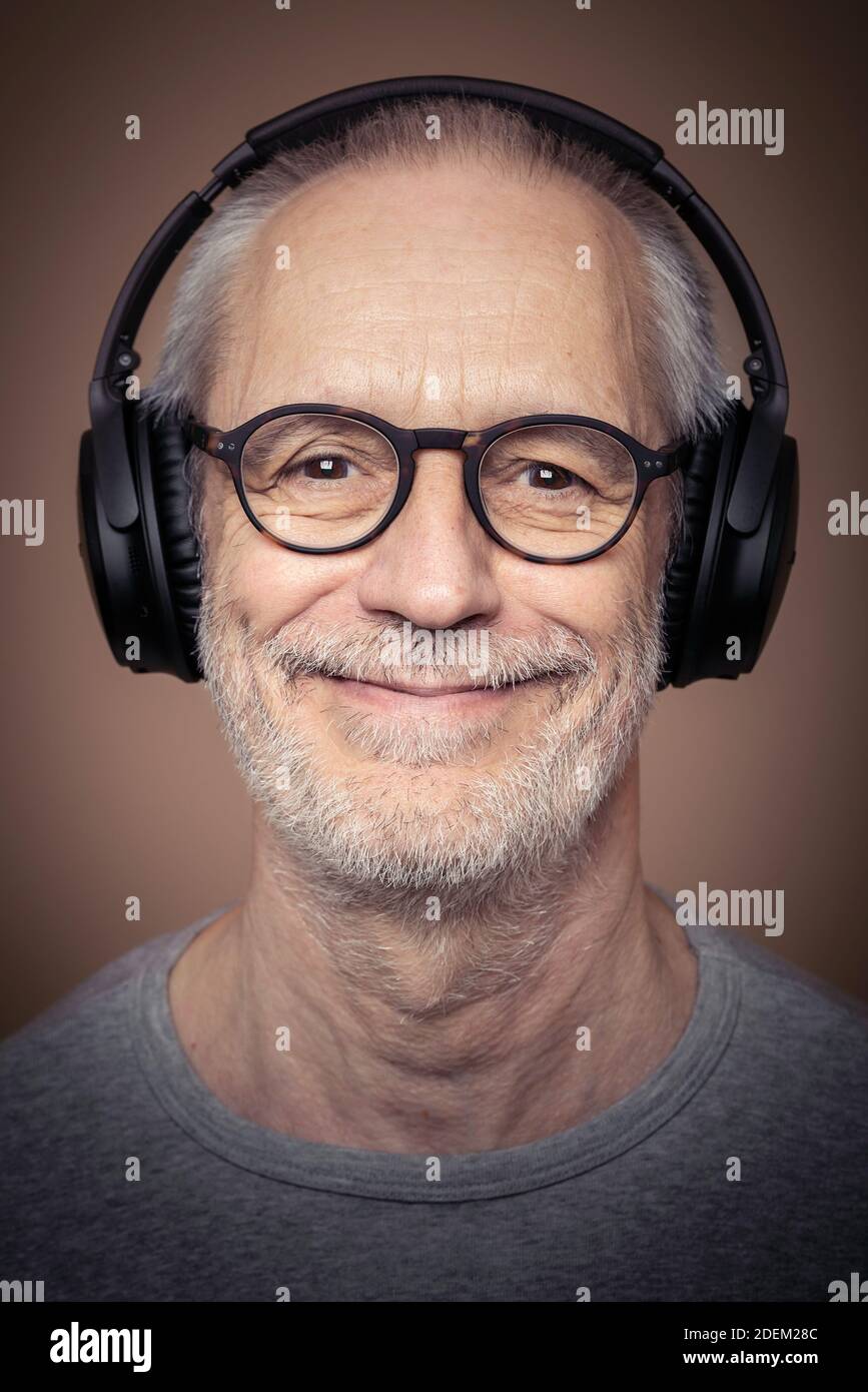 Headshot of adult man with beard wearing stereo headset and glasses. Stock Photo