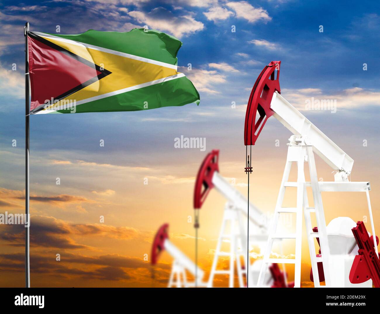 Oil rigs against the backdrop of the colorful sky and a flagpole with the flag of Guyana. The concept of oil production, minerals, development of new Stock Photo