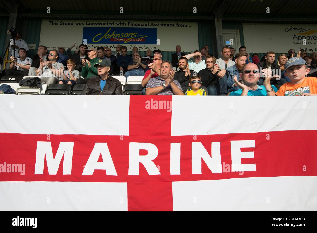 Home supporters watching the second-half action as Marine Football Club (in white), play Ilkeston FC in a Northern Premier League premier division match. The match was won by the home side by 3 goals to 1 and was watched by a crowd of 398. Marine are based in Crosby, Merseyside and have played at Rossett Park since 1903, the club having been formed in 1894. Stock Photo