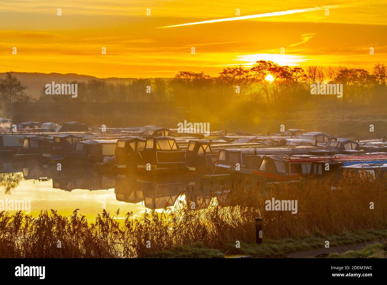 Rufford, Lancashire.  UK Weather 1st December, 2020. Cold frosty morning for houseboat residents on the marina at Rufford at the start of the official meteorological winter.   Coal fire stoves add smoke to the early morning fog over the Leeds Liverpool canal moorings.   By the meteorological calendar, the first day of winter is always 1 December and the season ends on 28 February Credit: MediaWorldImages/AlamyLiveNews Stock Photo