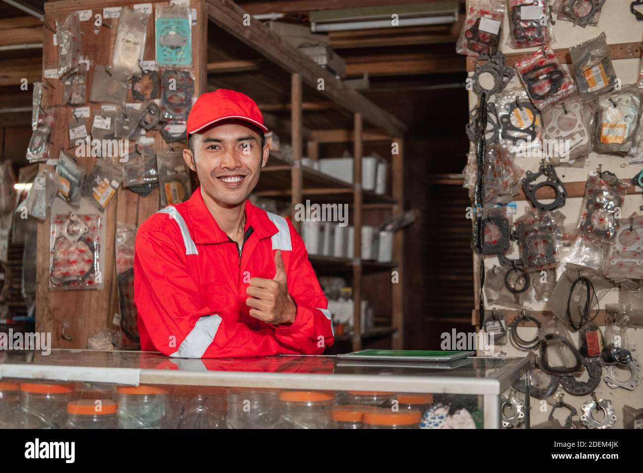 smiling mechanic wearing wearpack and hat with thumbs up standing in
