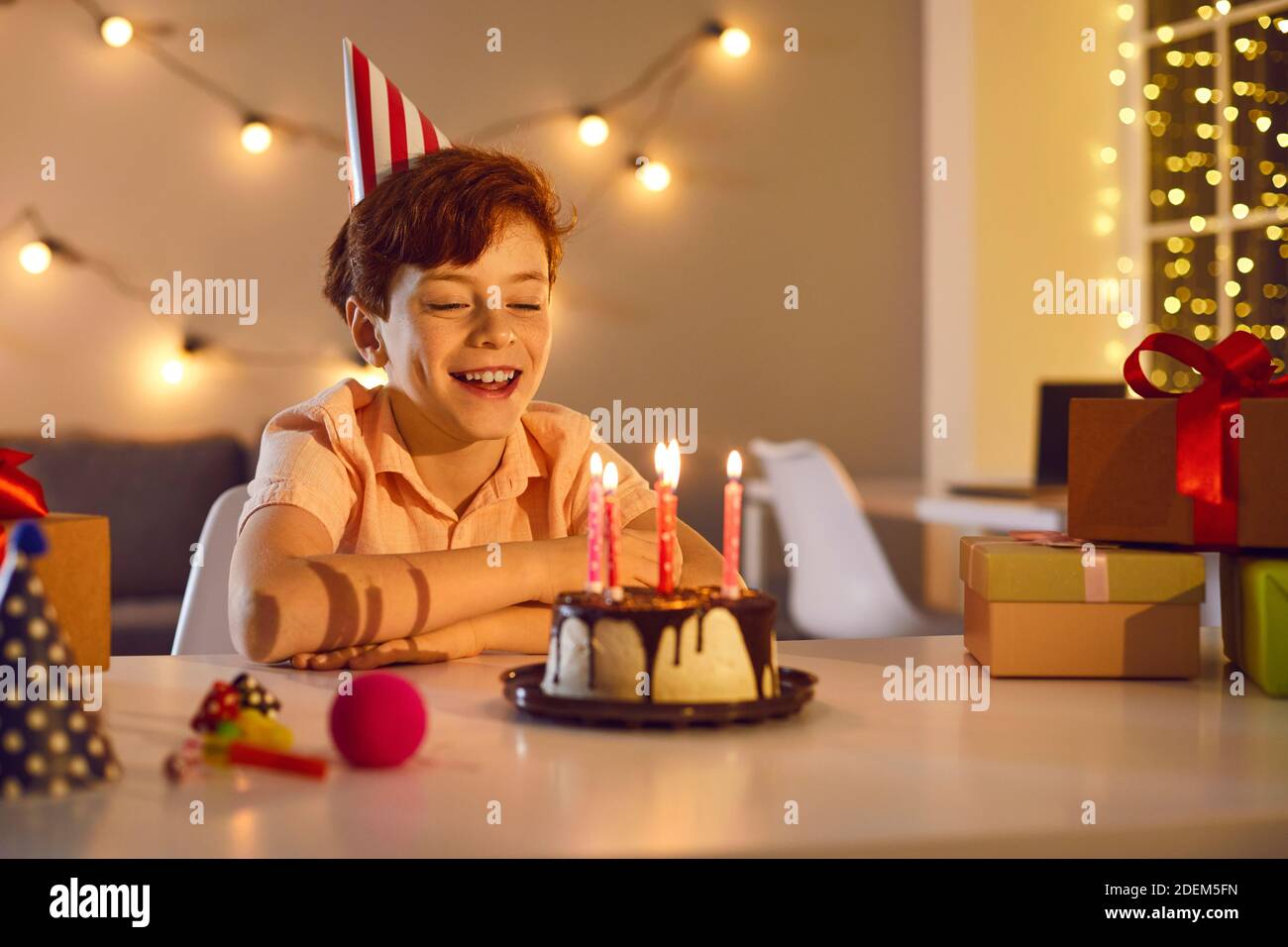 Happy little kid boy celebrating his birthday and blowing candles on