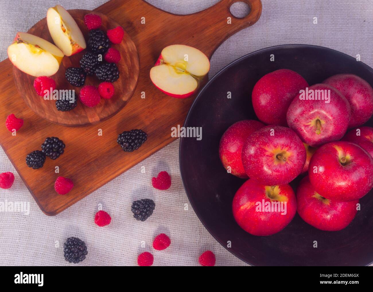 A high angle shot of ripe red apples with raspberries and blackberries ...