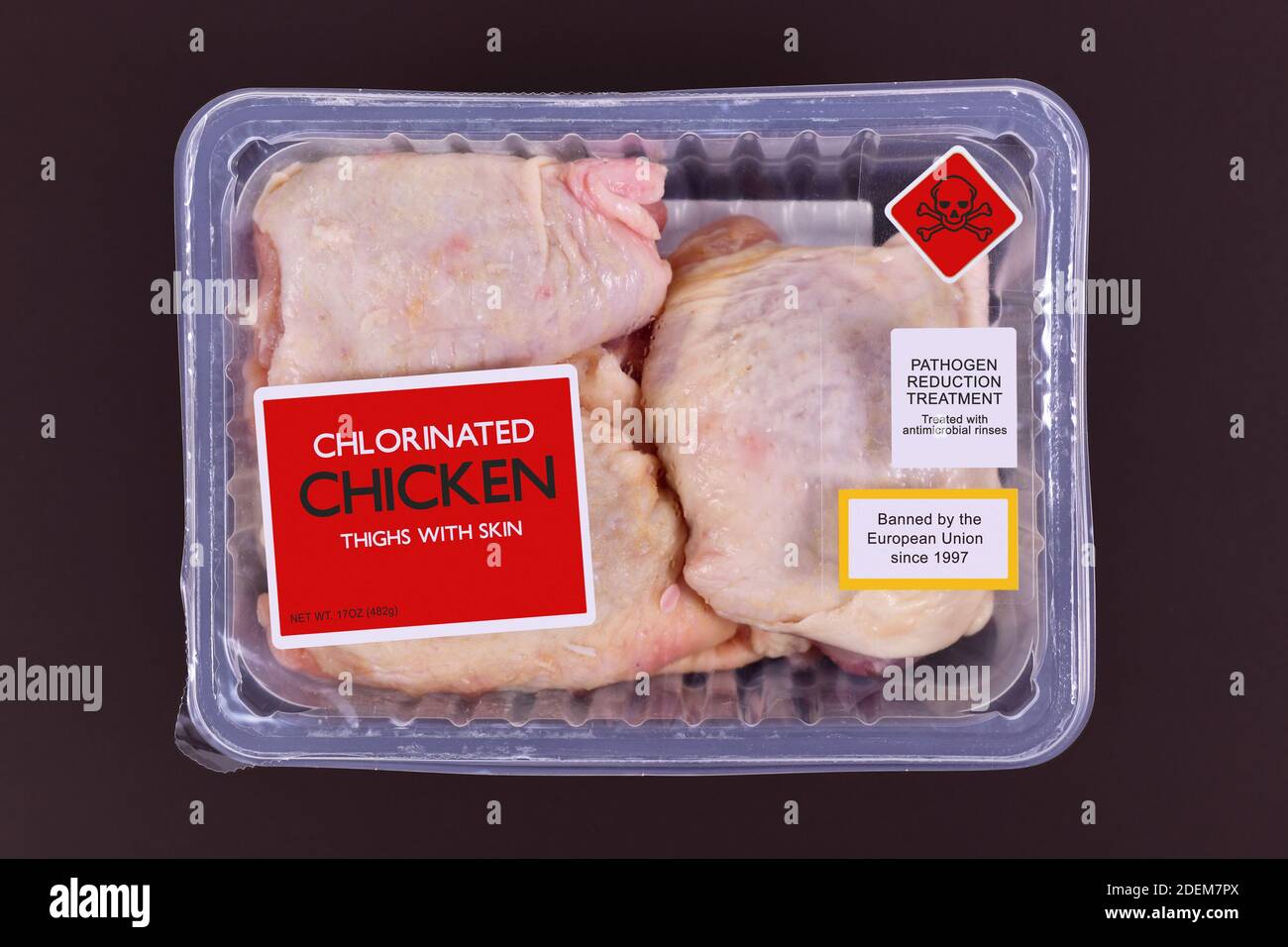 Concept for chlorinated chicken with pack of raw chicken thighs with warning label Stock Photo