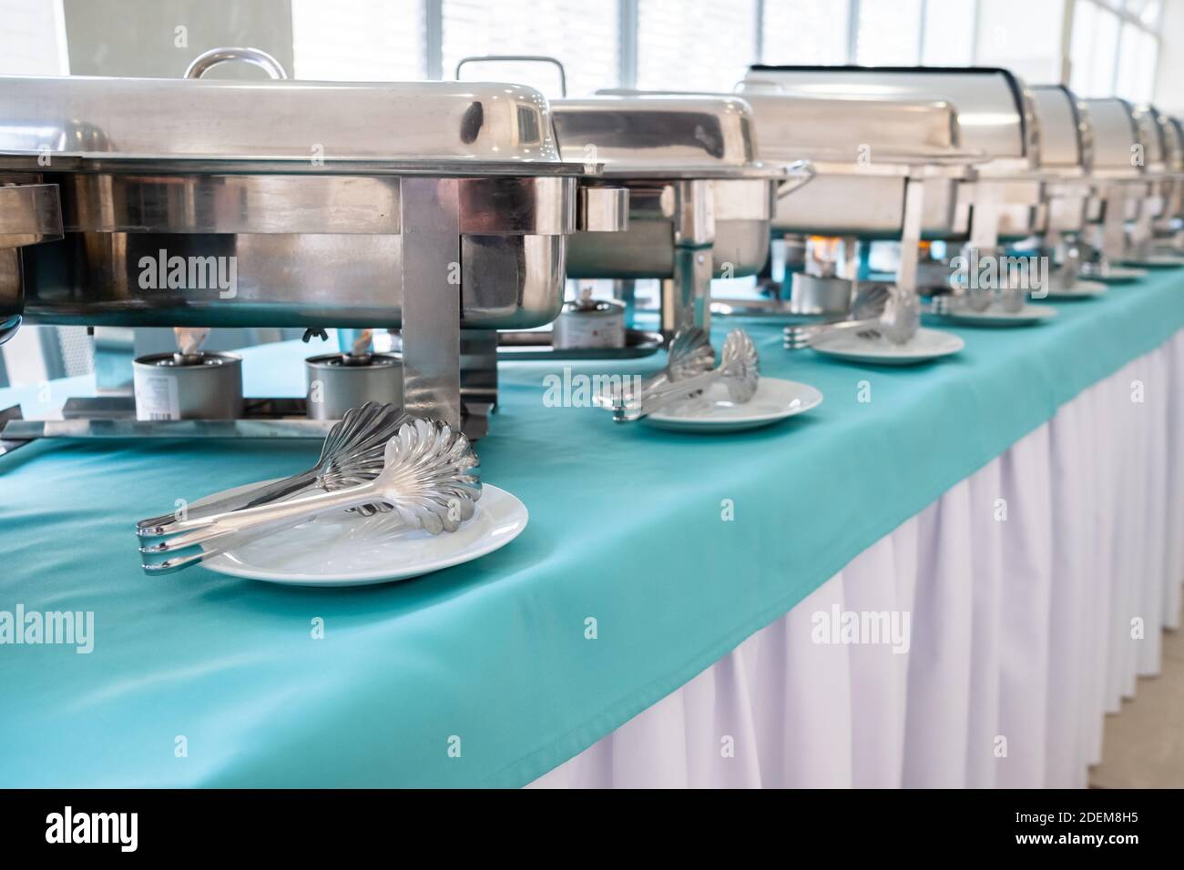 Shiny metal food warmers, stacks of plates and other kitchen equipment on  the table for a gourmet banquet or other service event. Catering Stock  Photo - Alamy