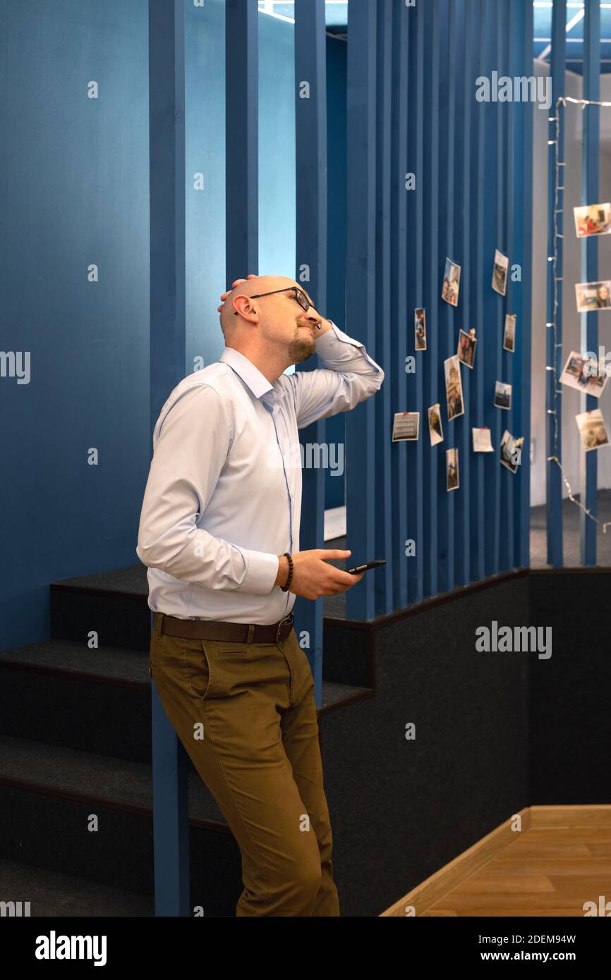 young bald man using smartphone and smiling. Looking up. Stock Photo