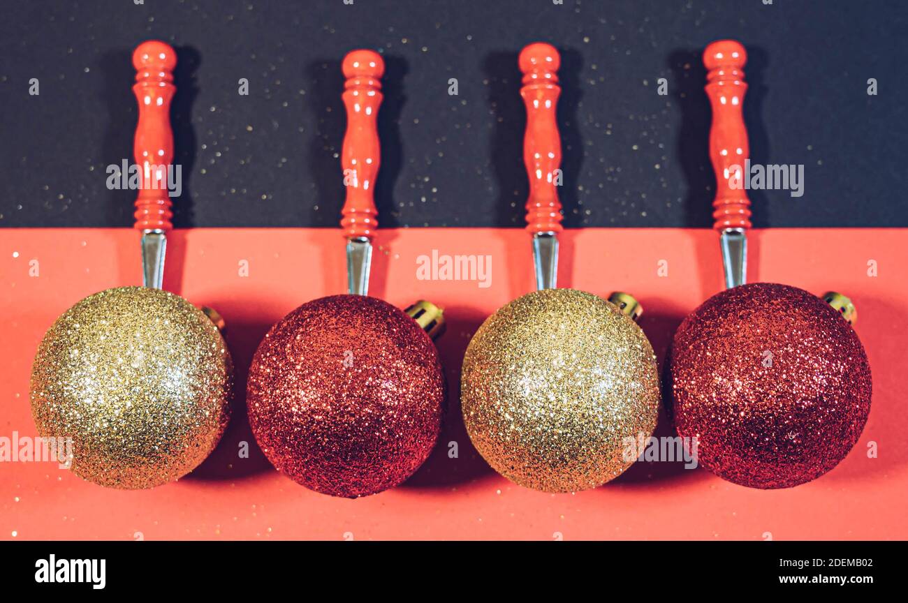 Red and golden christmas balls on a red rustic spoons isolated on a black and red background. Christmas concept. Christmas and New years background. Stock Photo