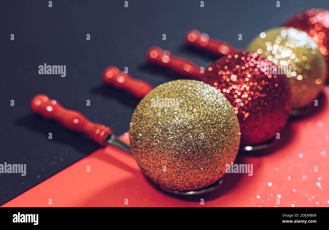 Red and golden christmas balls on a red rustic spoons isolated on a black and red background. Christmas concept. Christmas and New years background. Stock Photo