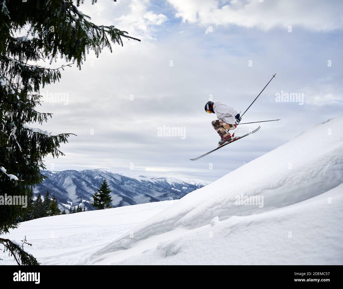 Side view of male skier making jump while sliding down snowcovered