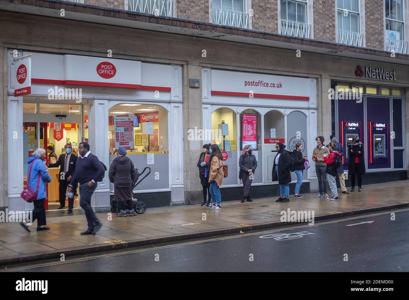 People line up outside the Post Office in Cambridge city centre, UK, 30