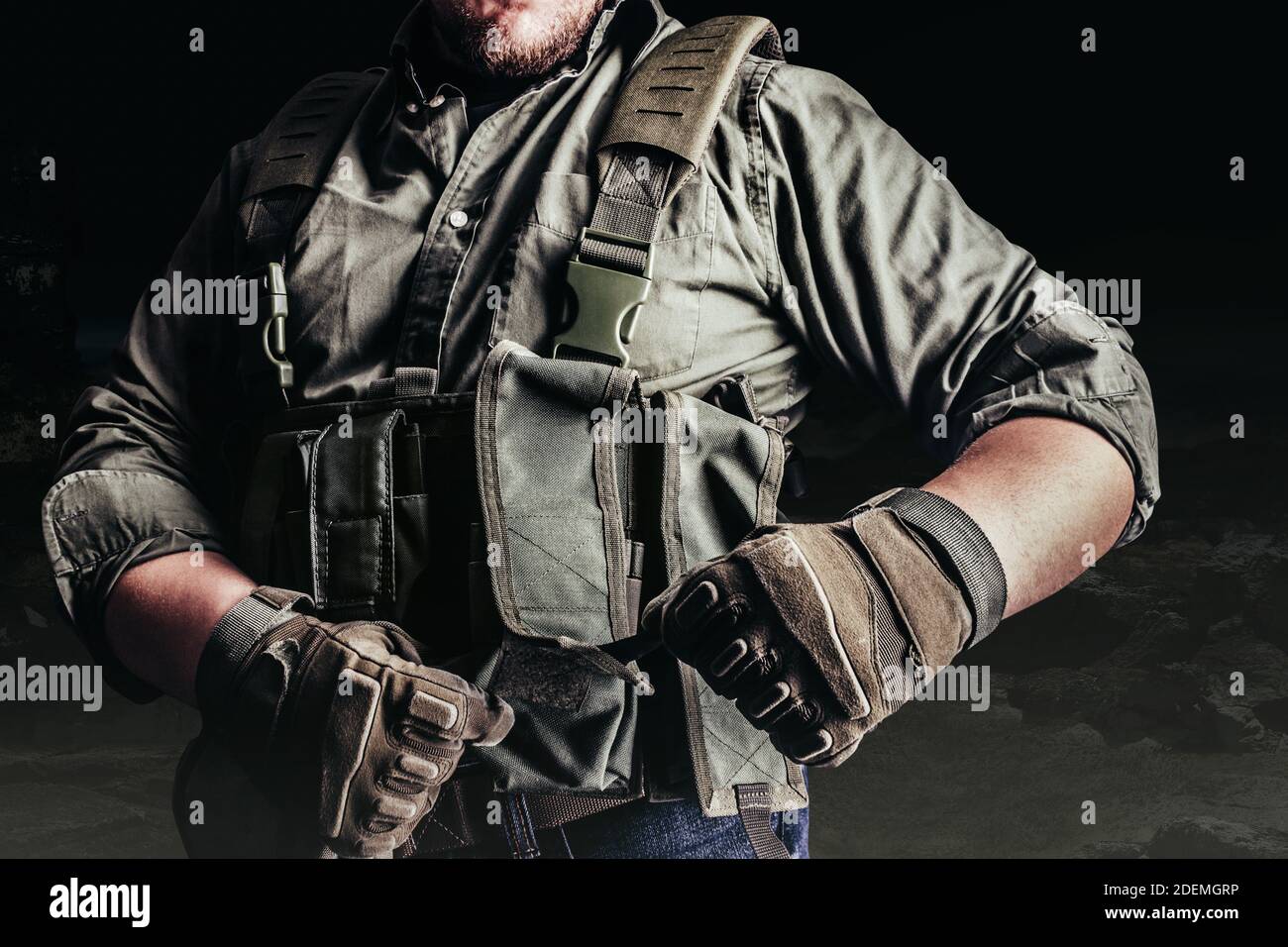 Soldier in tactical outfit and gloves putting on protective armor vest