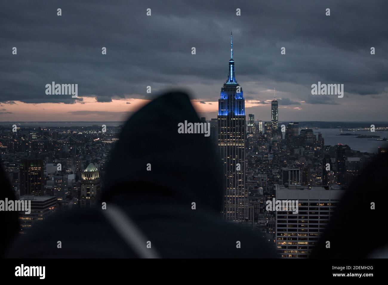 A man in a hoodie is looking at the building Stock Photo