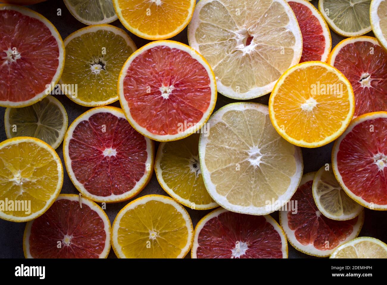 Red orange fruit circles on dark gray background. Citrus texture close up. Juicy oranges top view photo. Stock Photo