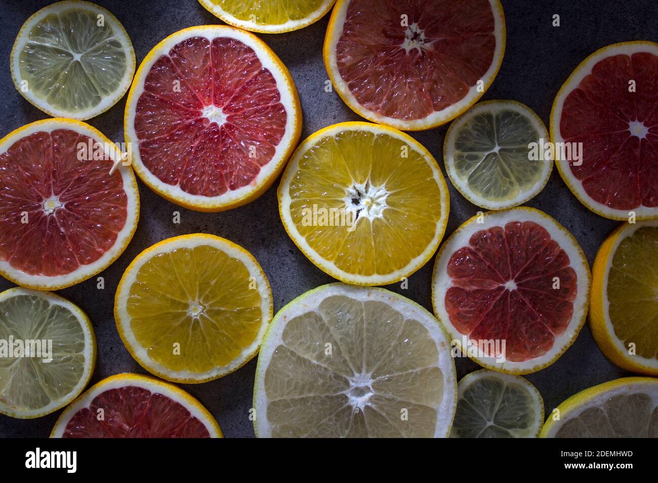 Red orange slices on a table. Fruit texture close up photo. Dark gray background with copy space. Stock Photo