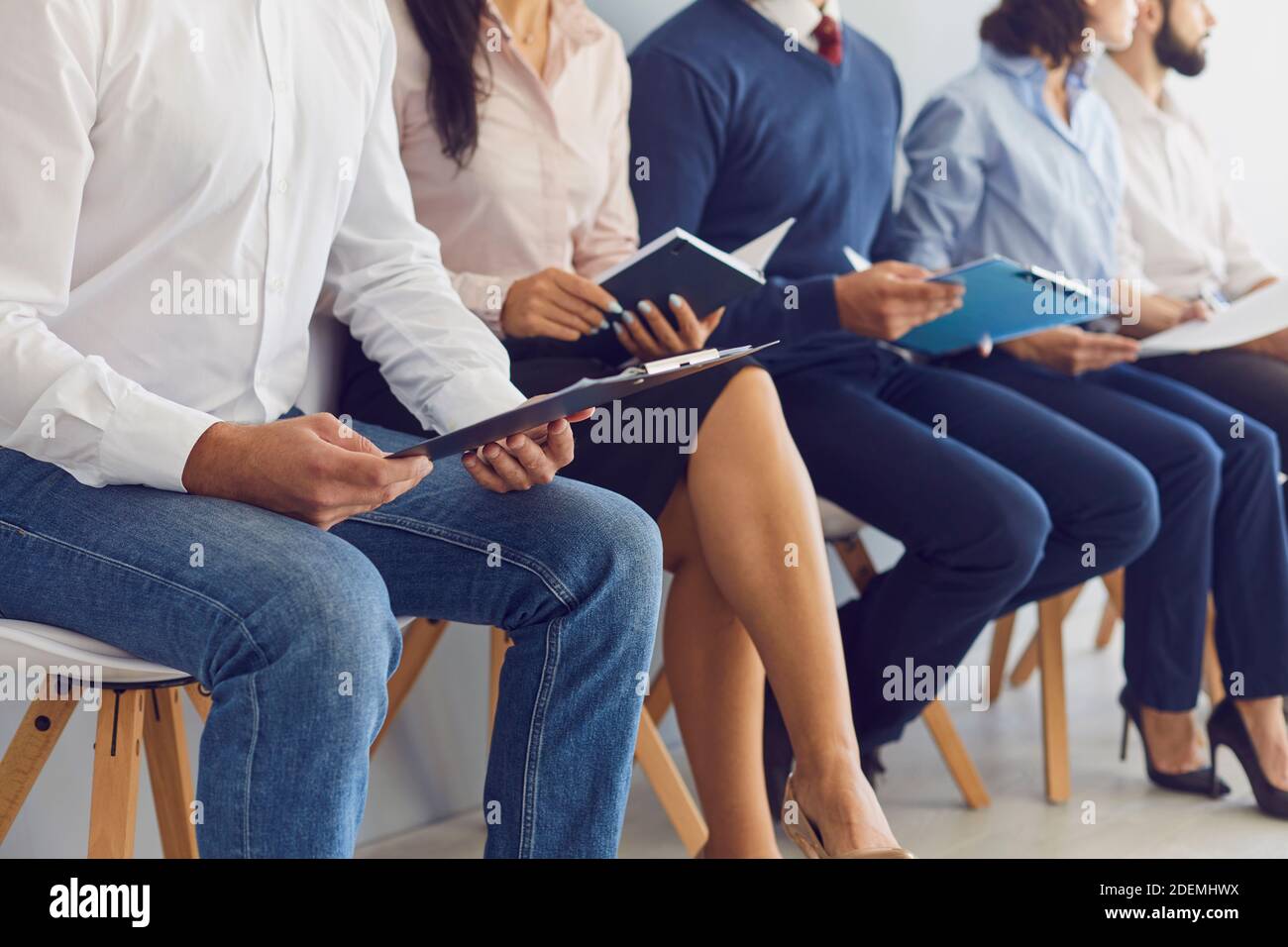 Job candidates sitting in row on chairs waiting for interview in modern finance company Stock Photo