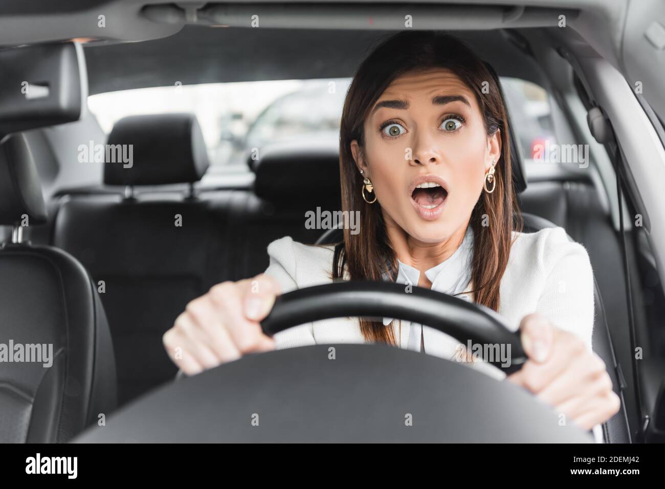 frightened woman screaming while driving car on blurred foreground