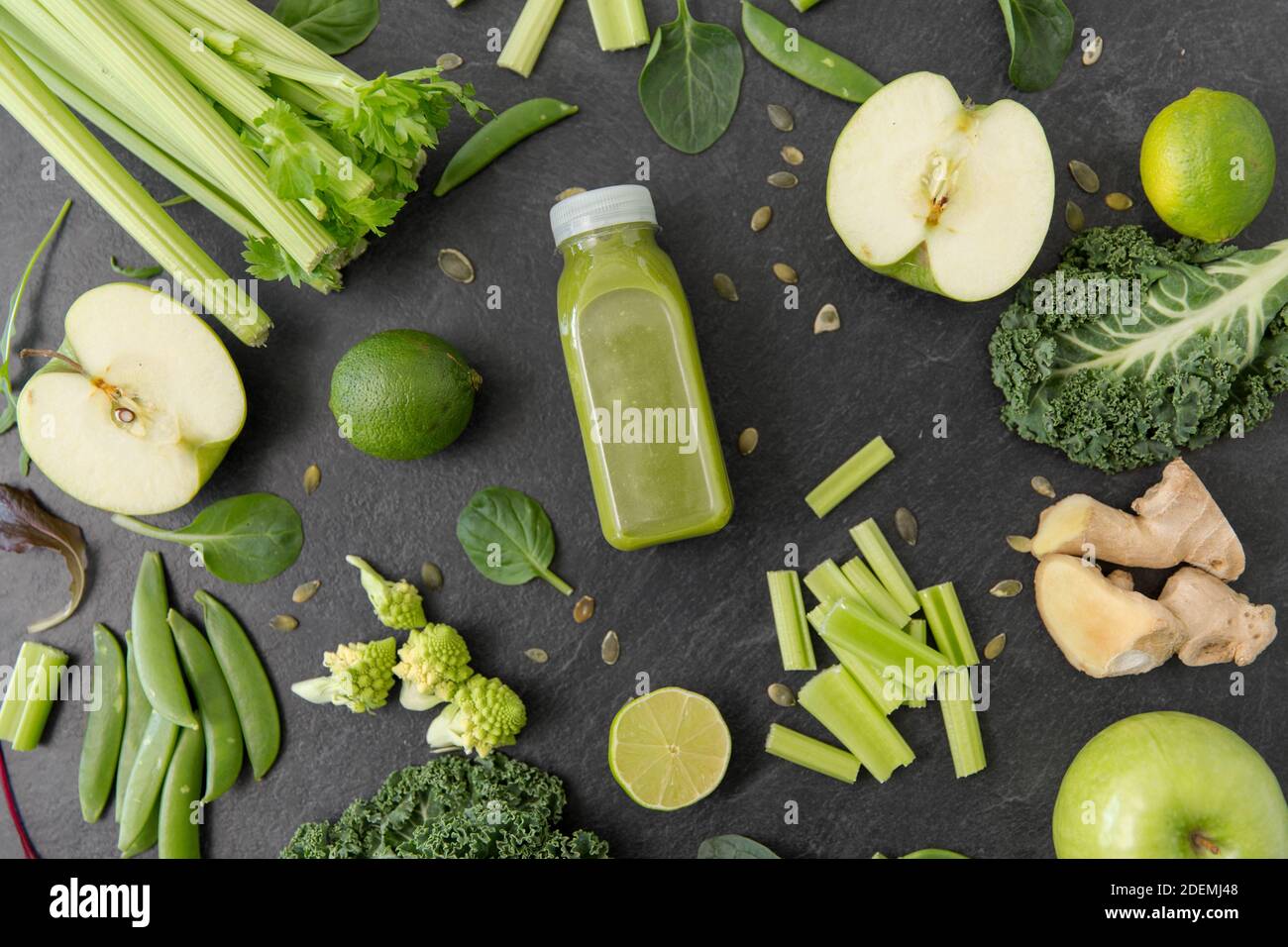 close up of bottle with green juice and vegetables Stock Photo