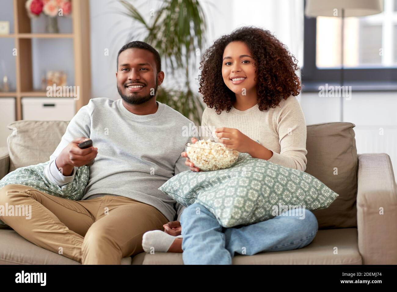 african couple with popcorn watching tv at home Stock Photo - Alamy