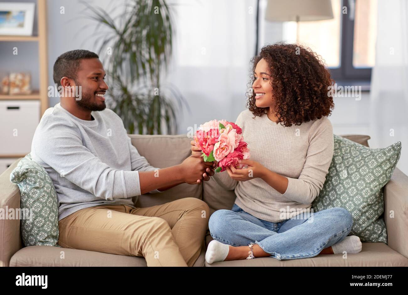 happy couple with bunch of flowers at home Stock Photo