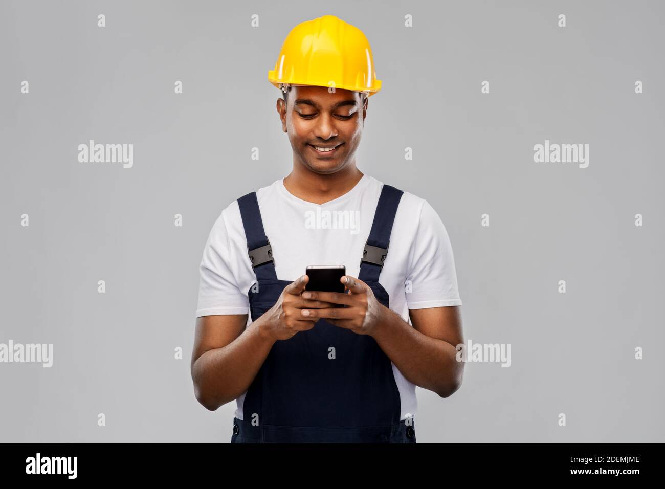 happy indian or builder in helmet using smartphone Stock Photo