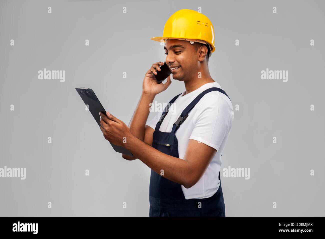indian builder with clipboard calling on cellphone Stock Photo