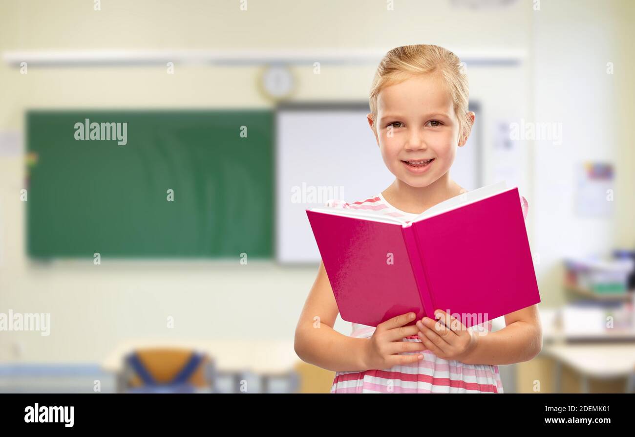 smiling little girl reading book at school Stock Photo - Alamy