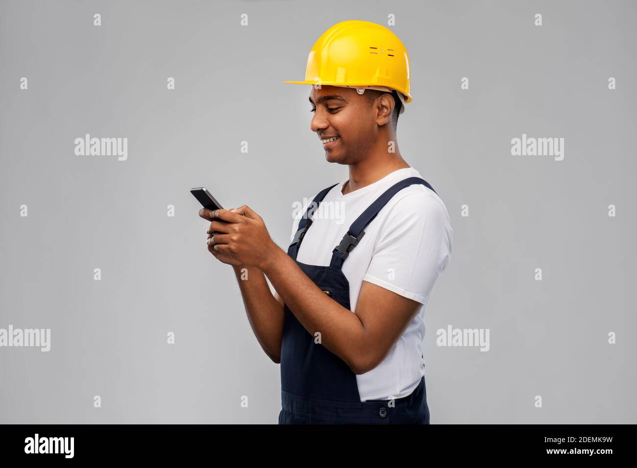 happy indian or builder in helmet using smartphone Stock Photo