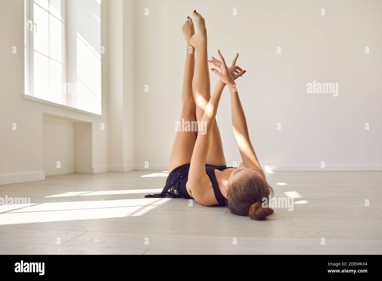 Slender female practicing rhythmic gymnastics exercises or dancing in a bright studio. Stock Photo