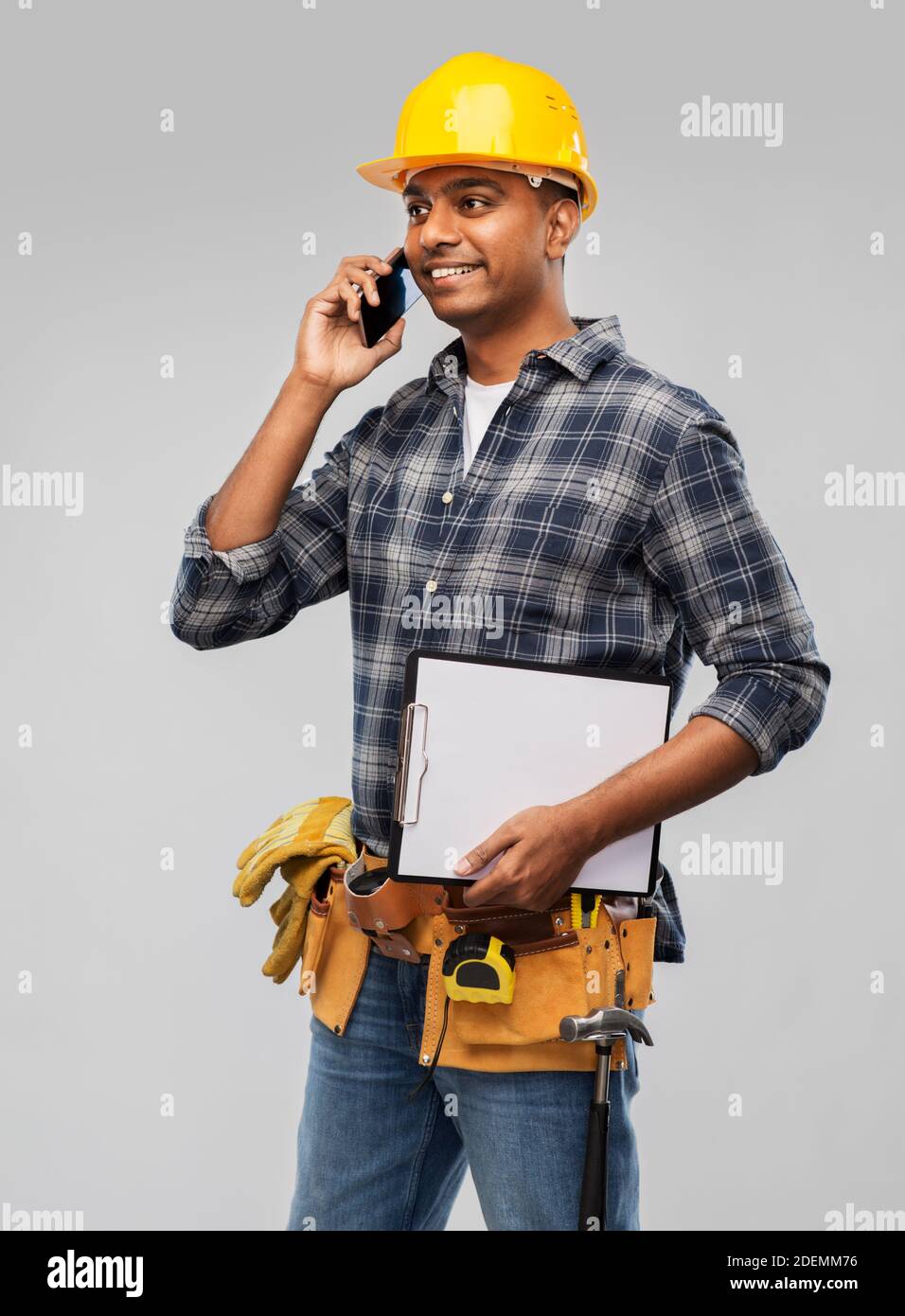 indian builder in helmet calling on smartphone Stock Photo