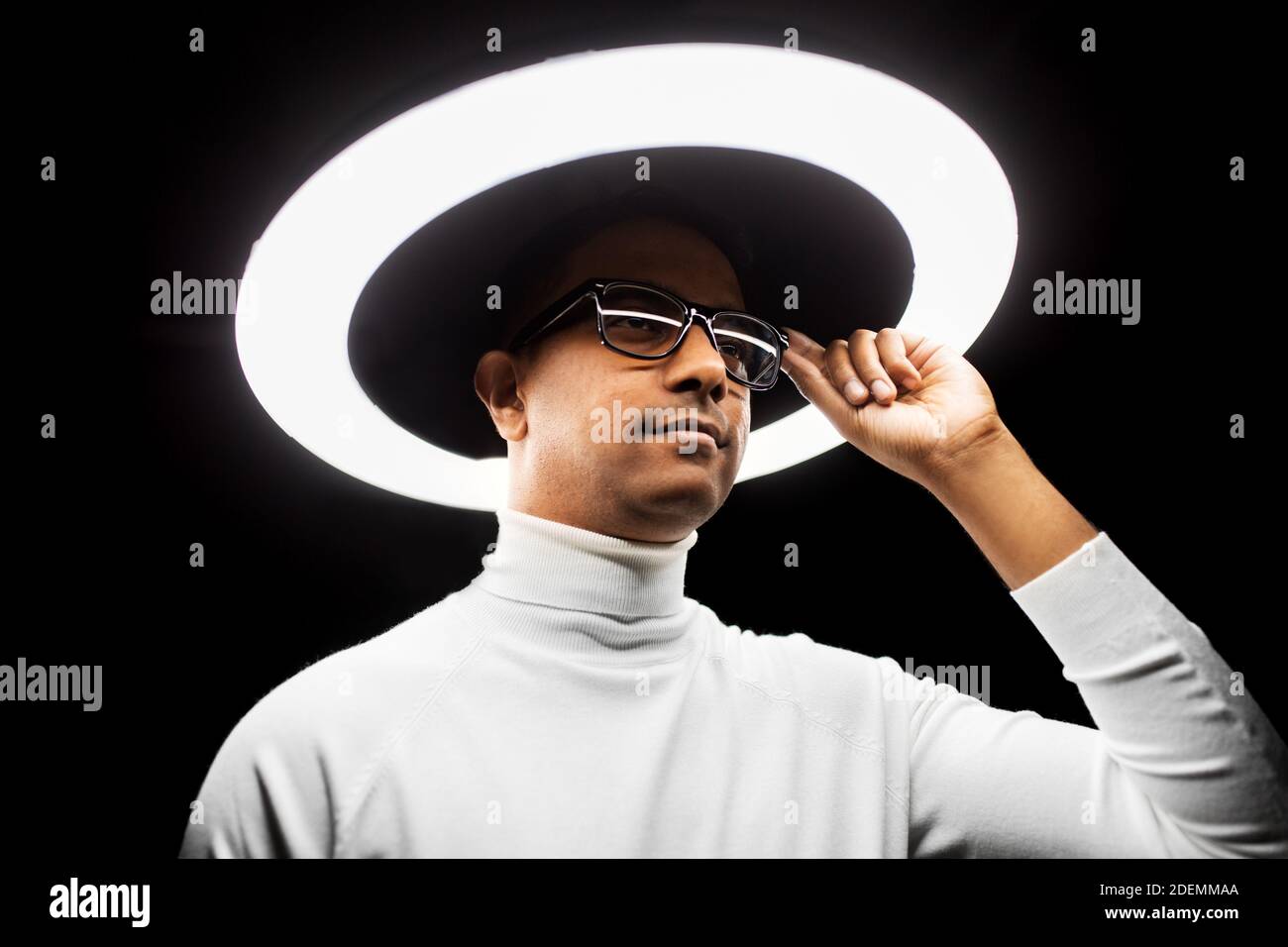 man in glasses under white illumination over black Stock Photo