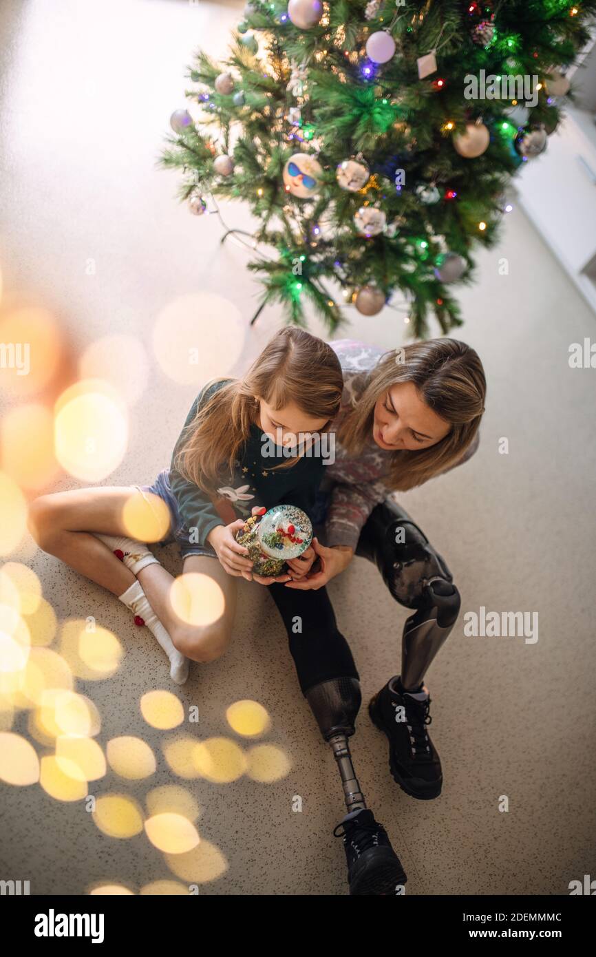 Disabled woman and her daughter sit under Christmas tree. Stock Photo