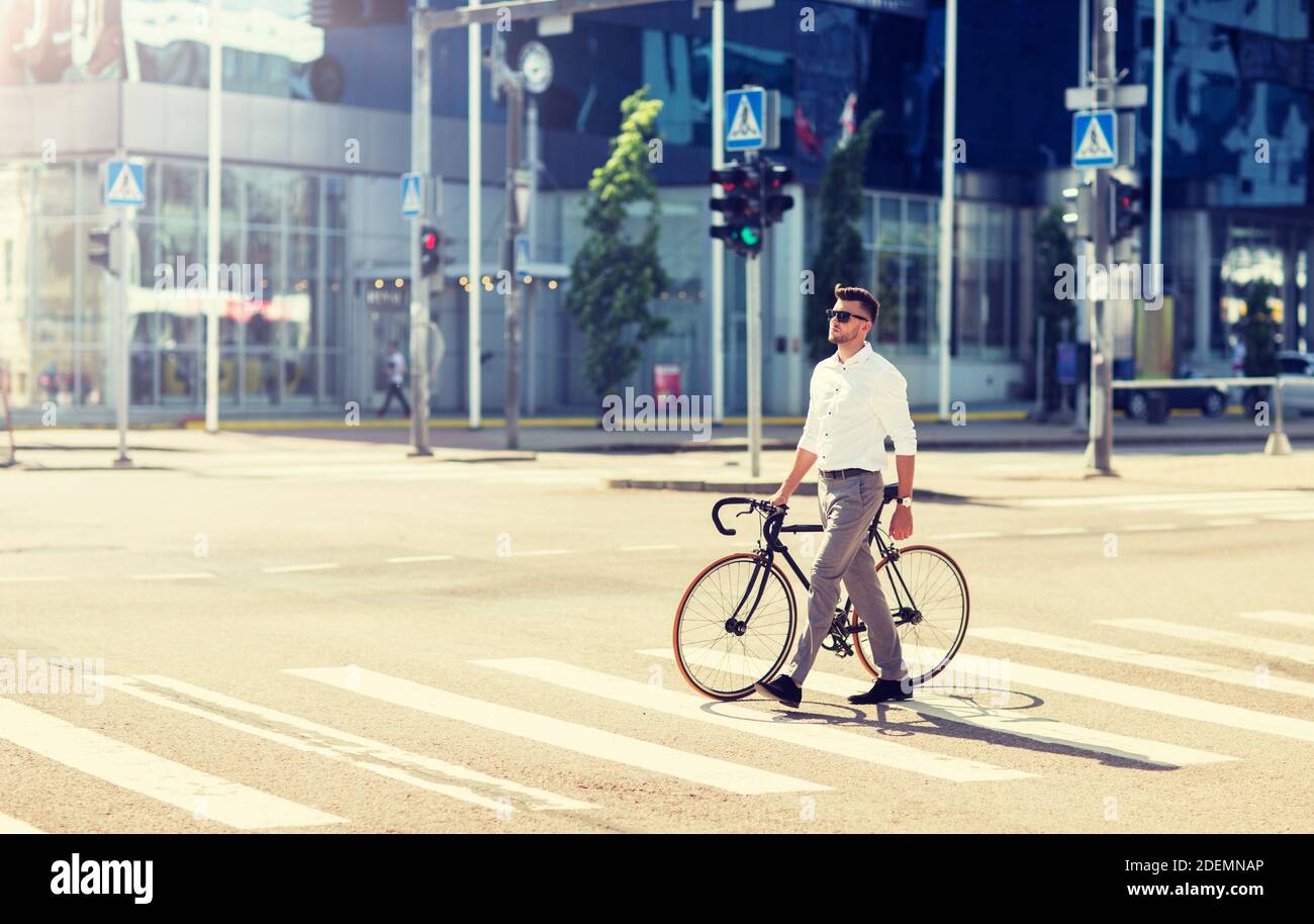 young man with bicycle on crosswalk in city Stock Photo